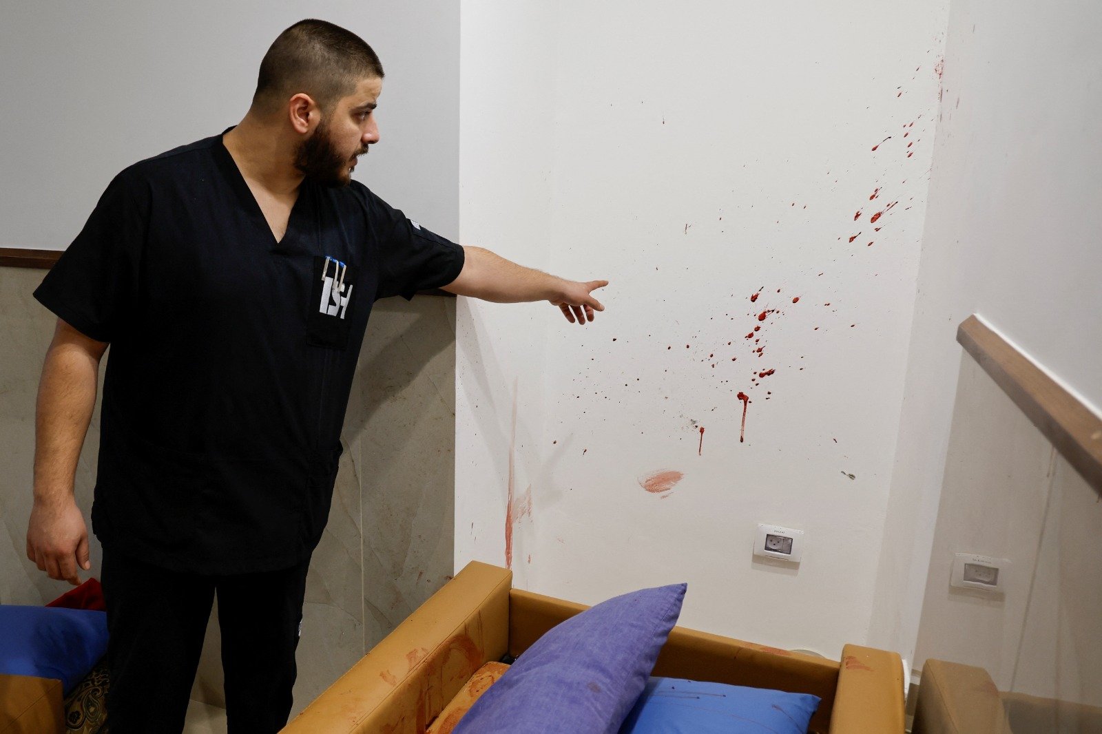 一名男子指著约旦河西岸杰宁一家医院内，3名巴勒斯坦人在以色列袭击中被杀现场的血迹。（图取自路透社）